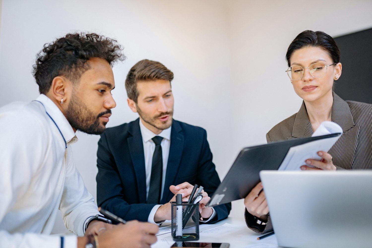 Three coworkers reviewing a laptop and papers during a meeting at a table