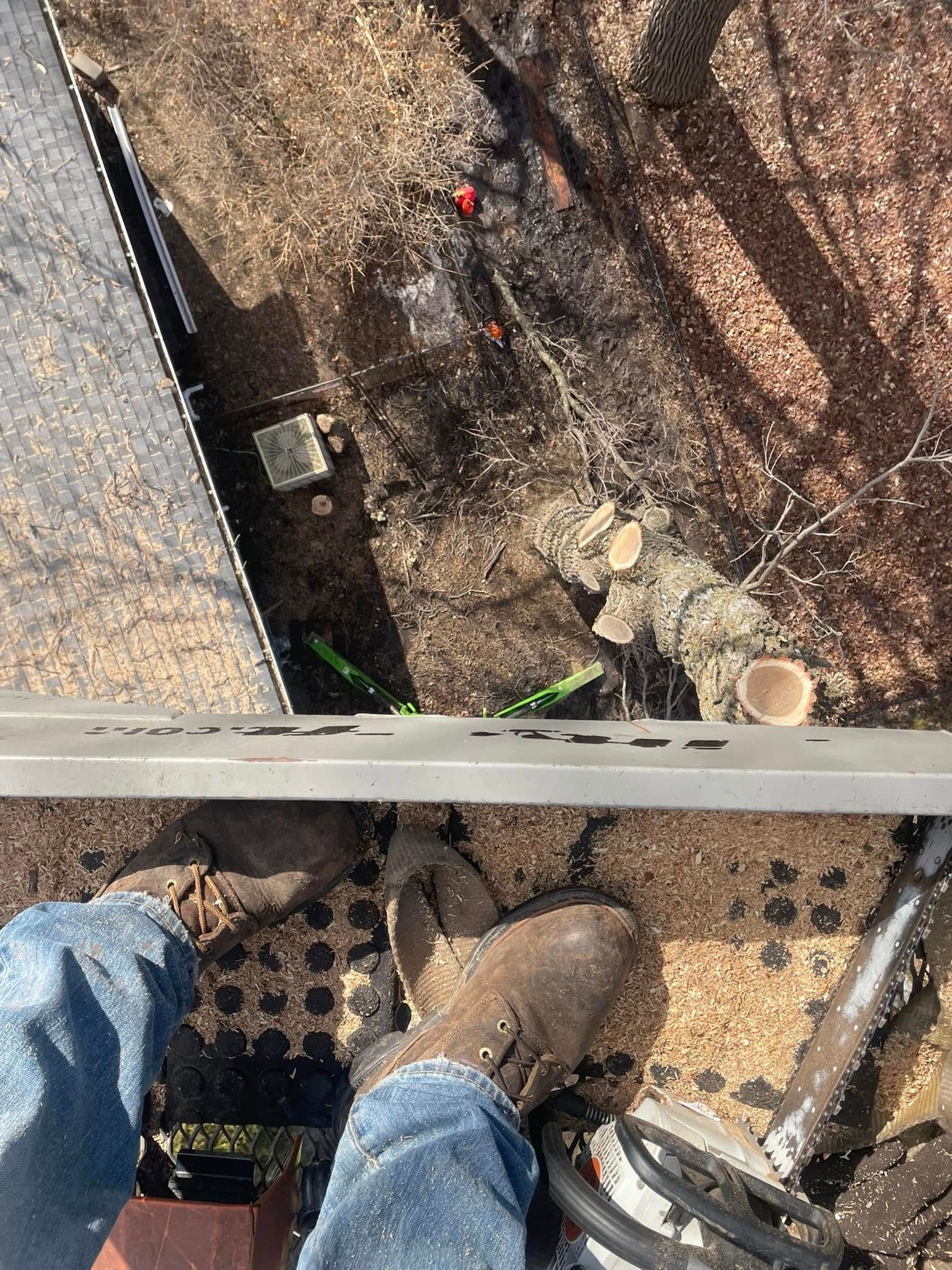 A person is standing on a roof looking down at the ground.