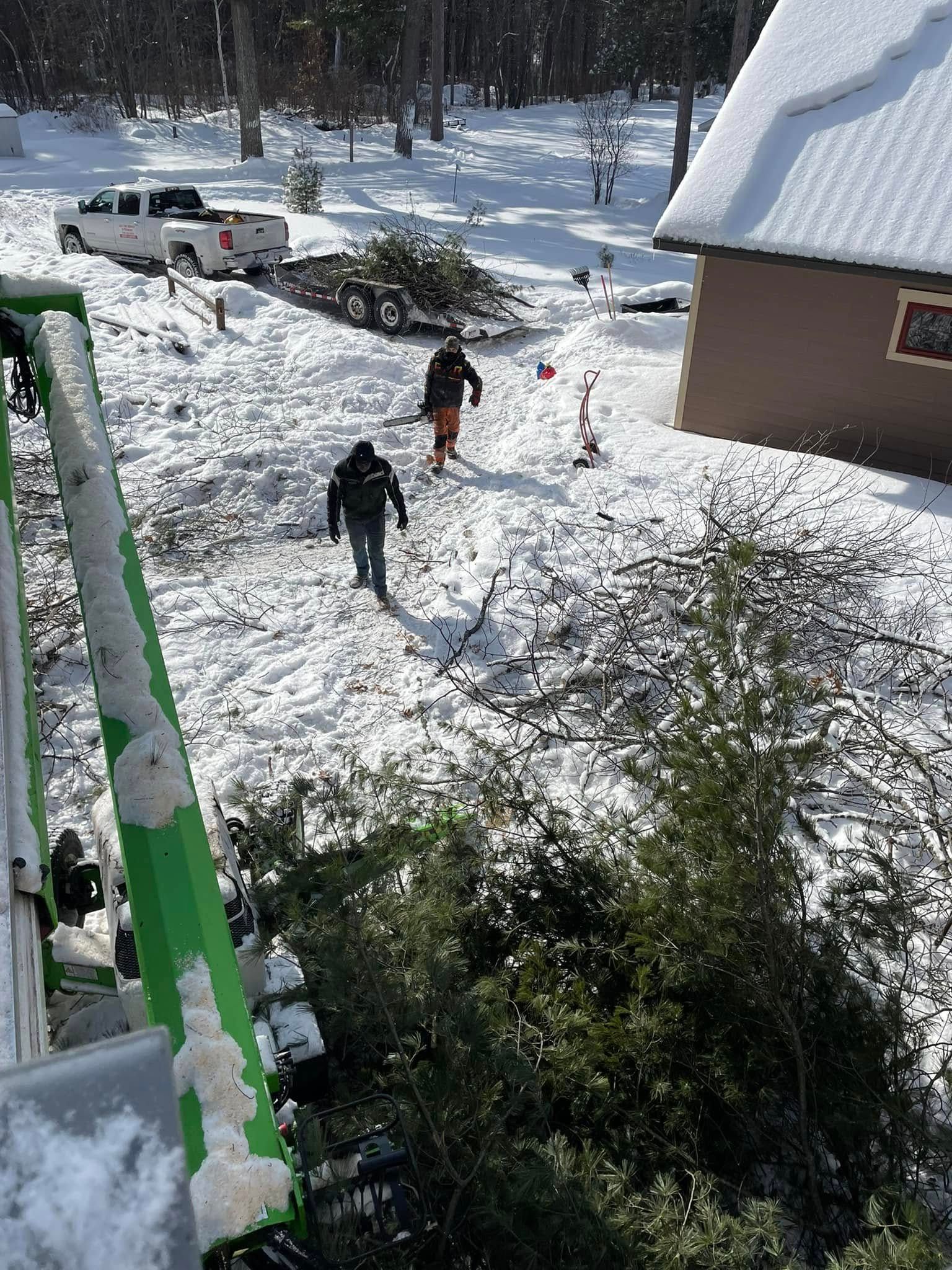 A group of people are standing in the snow near a house.