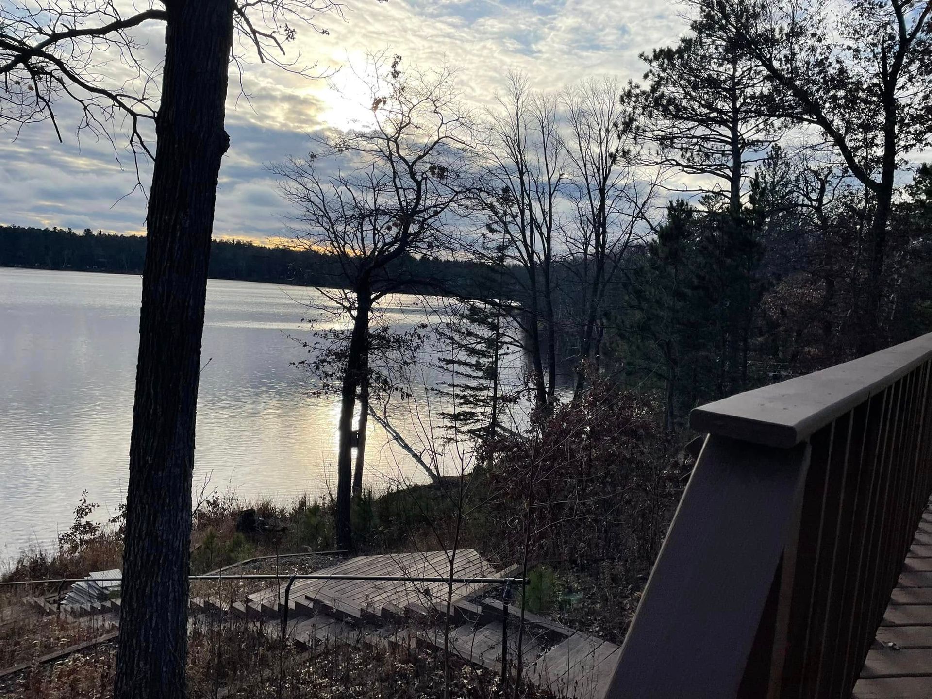 A view of a lake from a deck with trees in the foreground.