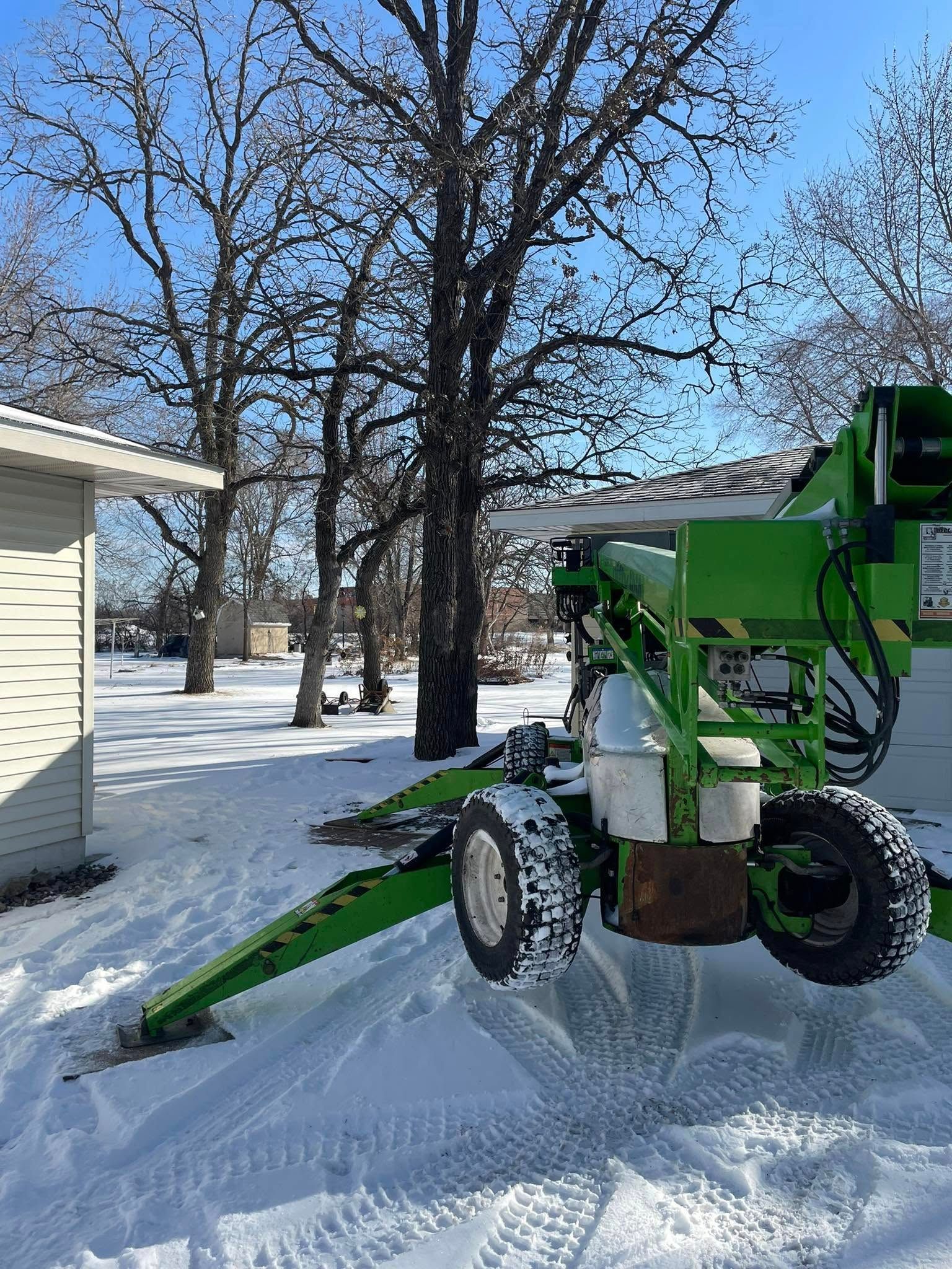 A green machine is parked in the snow in front of a house.