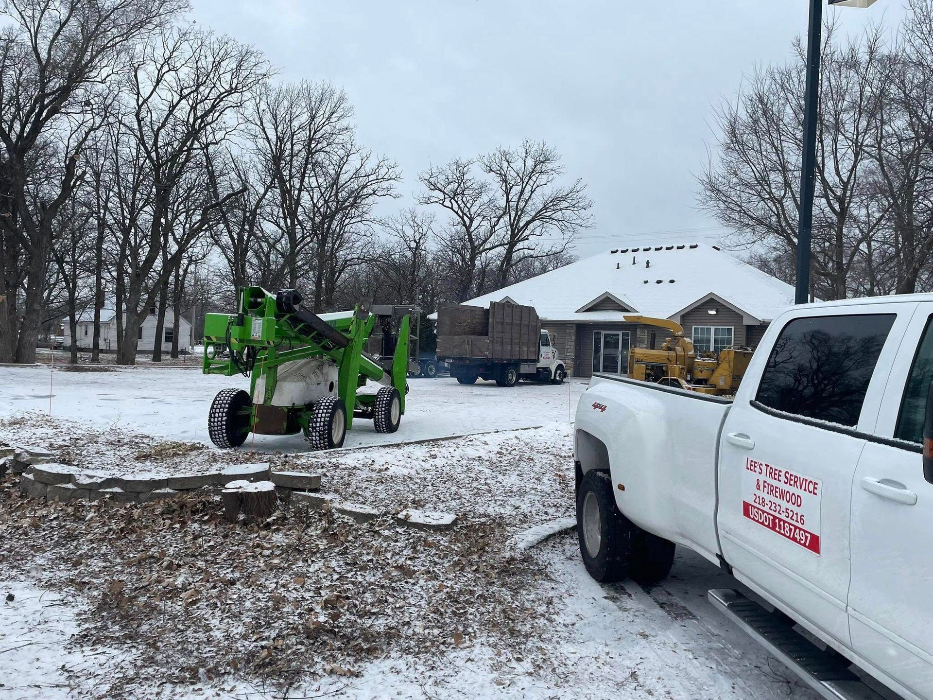 A white truck is parked in the snow next to a green machine.