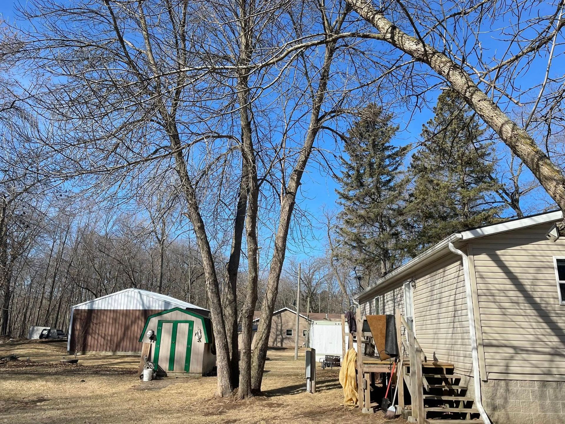 A house is sitting in the middle of a field with trees in the background.