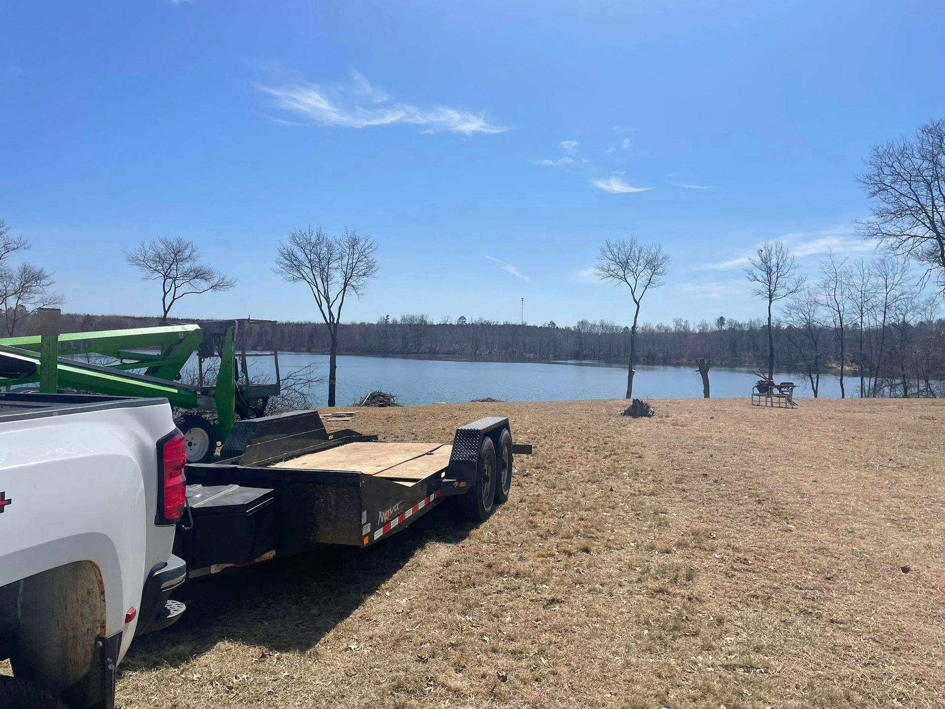 A truck with a trailer attached to it is parked in a field next to a lake.