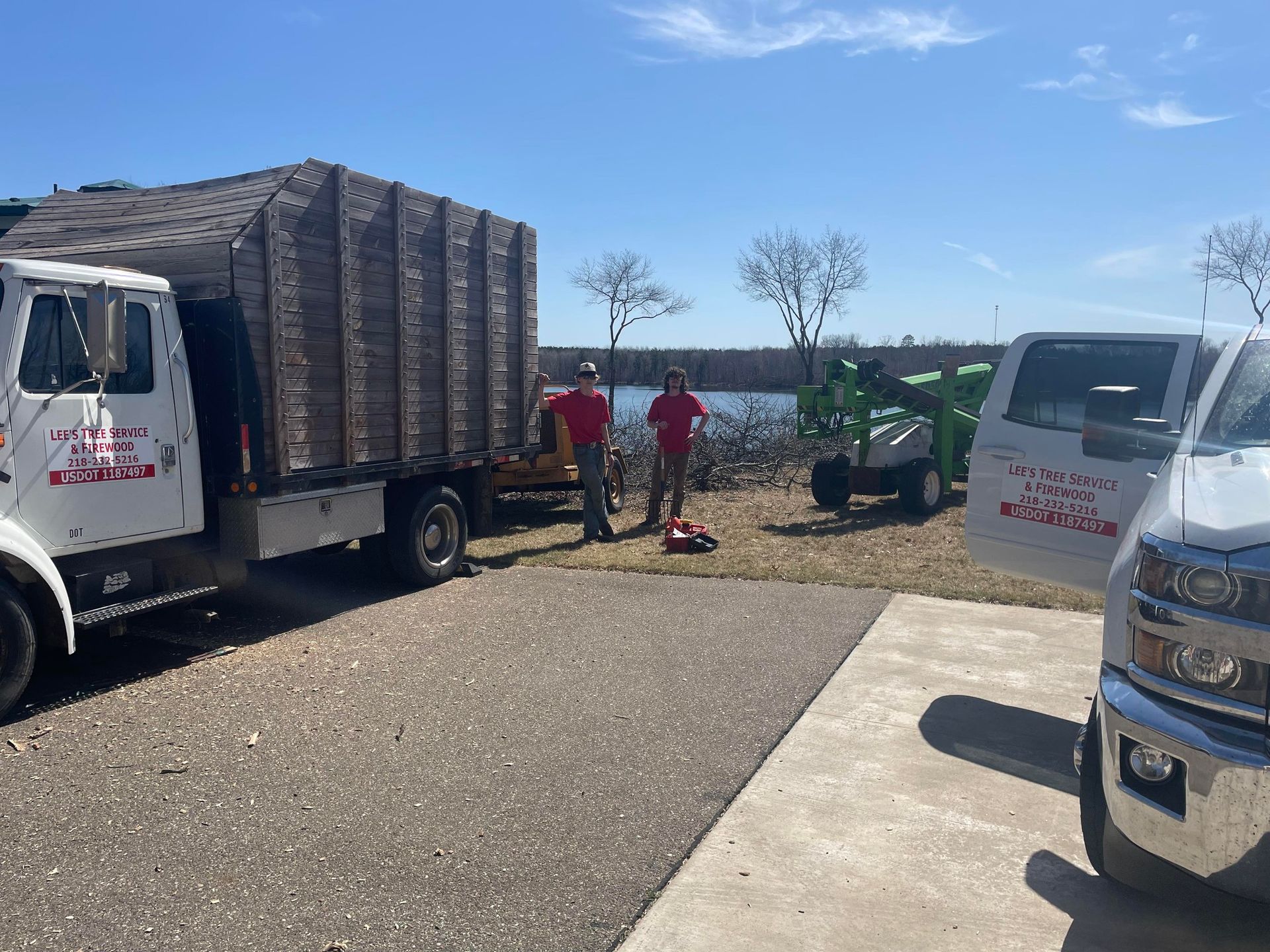 Two men are standing next to a truck and a van in a parking lot.