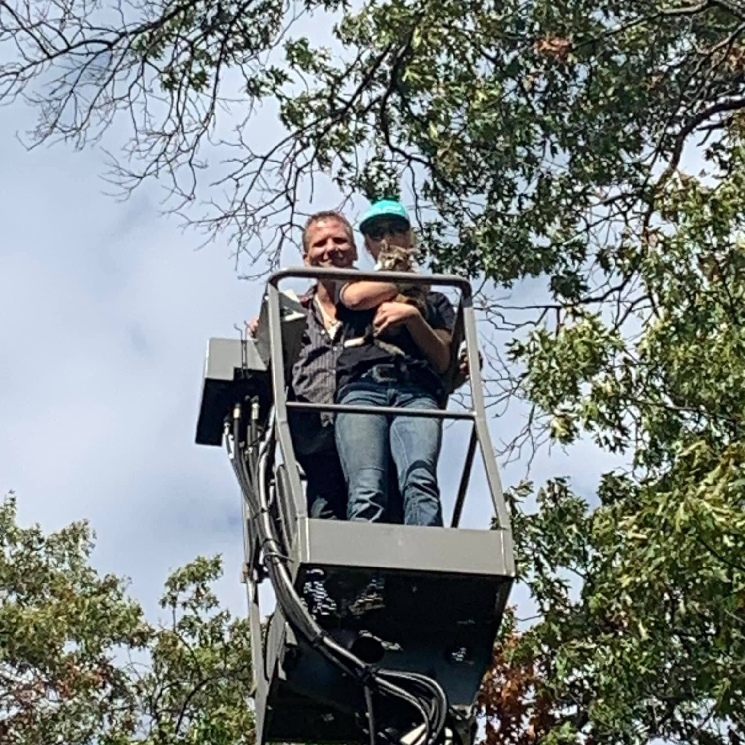 A man and a woman are sitting in a bucket on a crane.