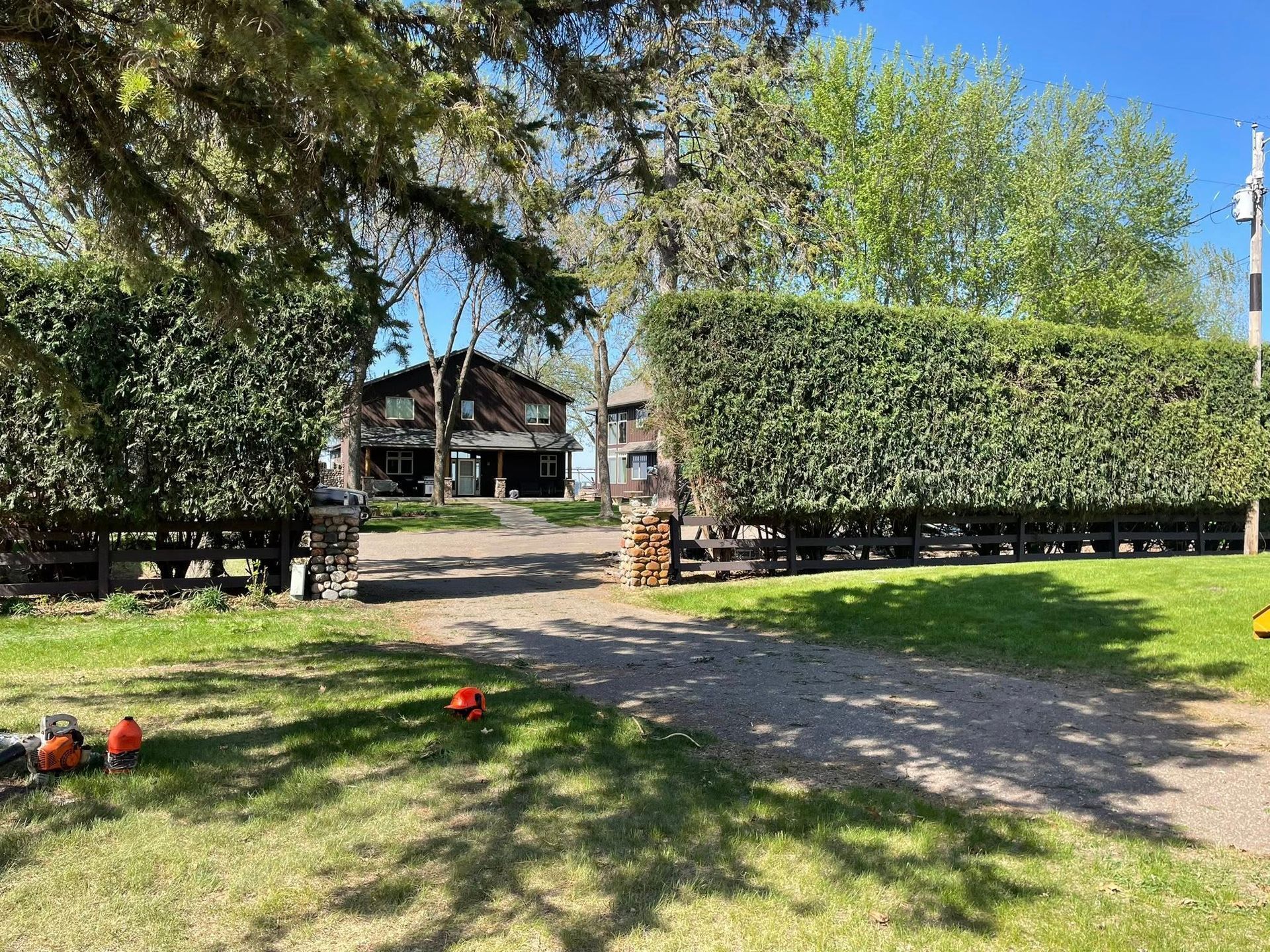 A large house is sitting in the middle of a lush green field surrounded by trees.