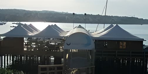 Ristorante sull'acqua con numerose strutture bianche simili a tende e sullo sfondo il lungomare.