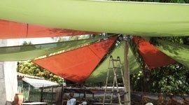 Tendalino in tessuto colorato, arancione e verde, che copre un'area esterna; scala sottostante.