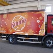 Camion per la consegna di bibite Kinnie con grafica arancione e marrone, parcheggiato al chiuso.