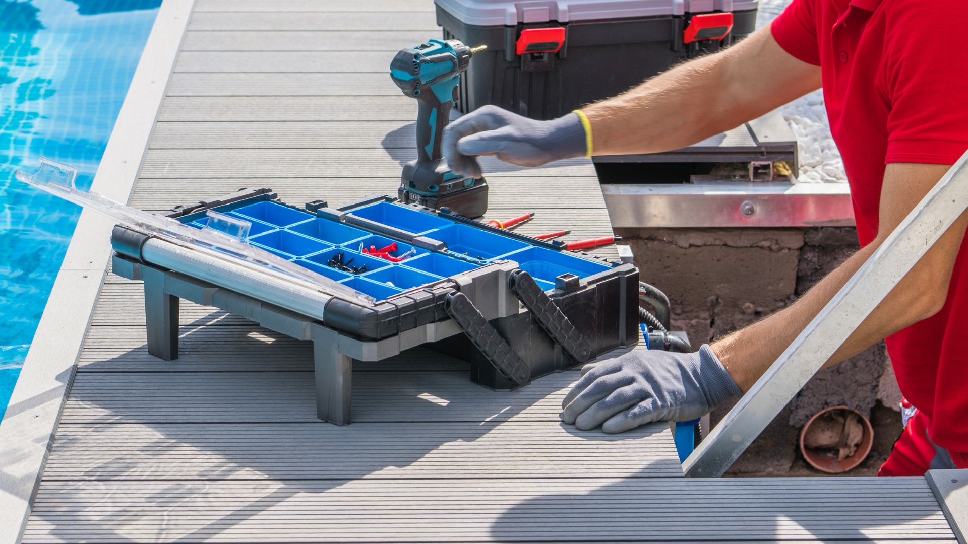 A man is working on a swimming pool with a drill and a toolbox.