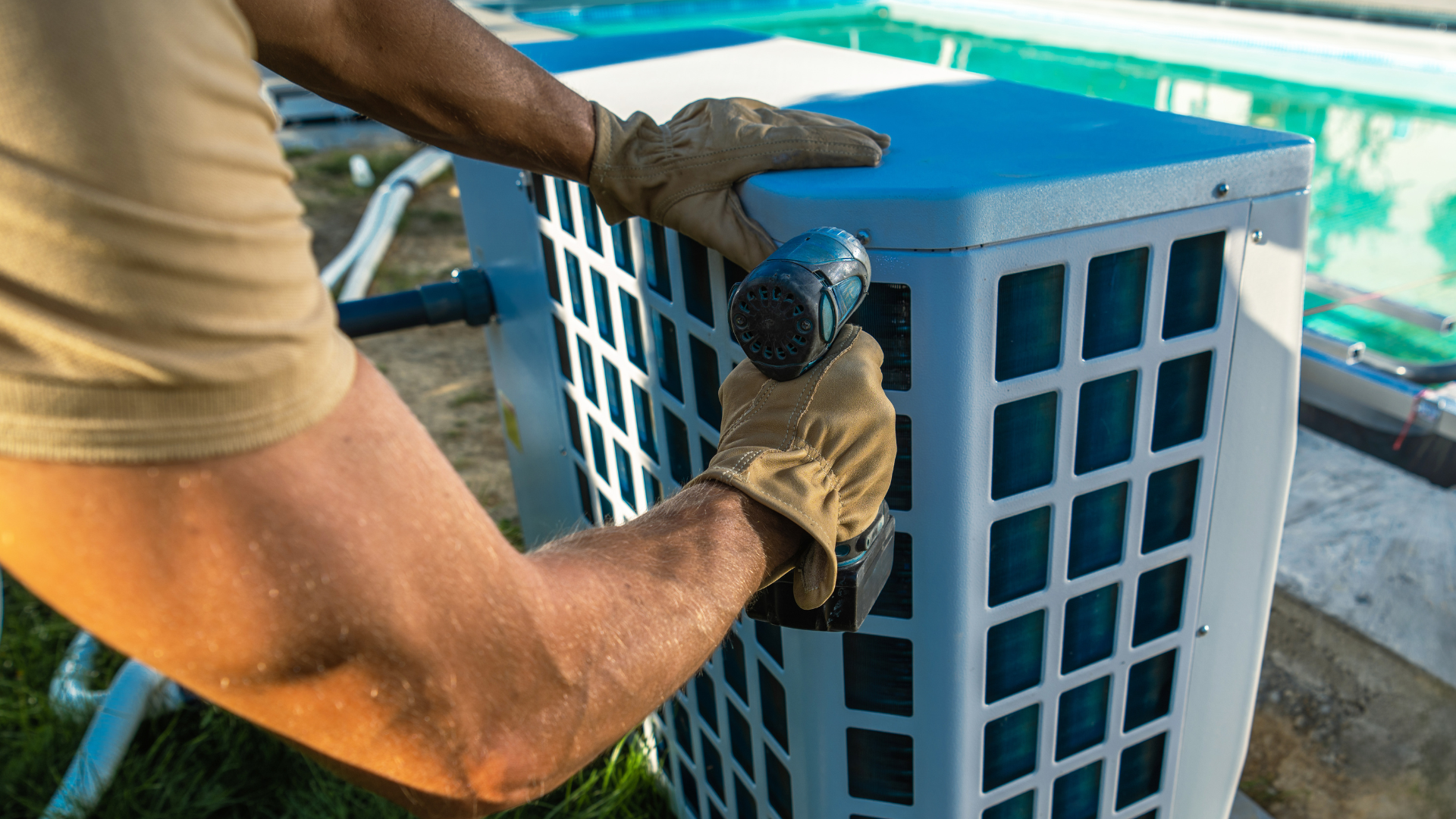 A man is working on an air conditioner outside of a swimming pool.