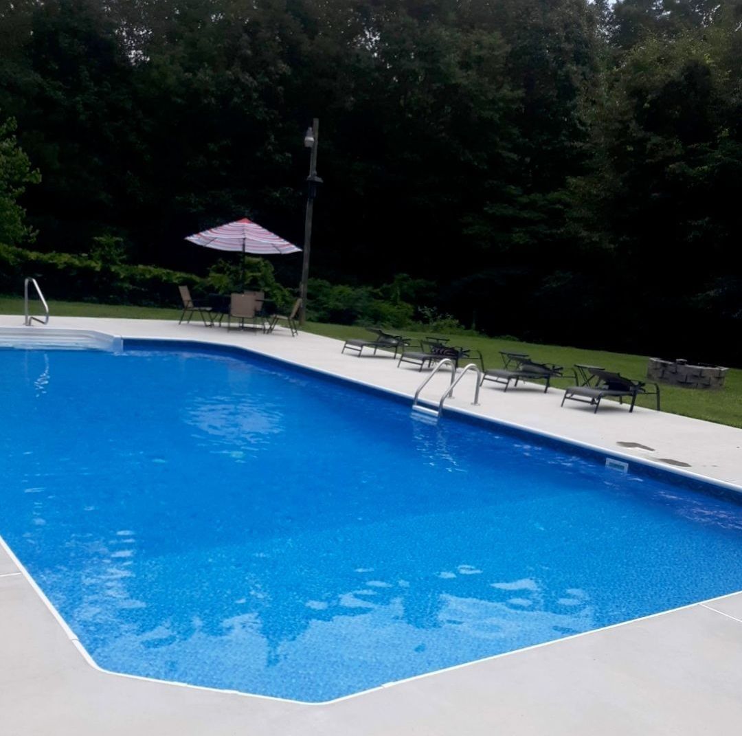 A large swimming pool surrounded by chairs and umbrellas