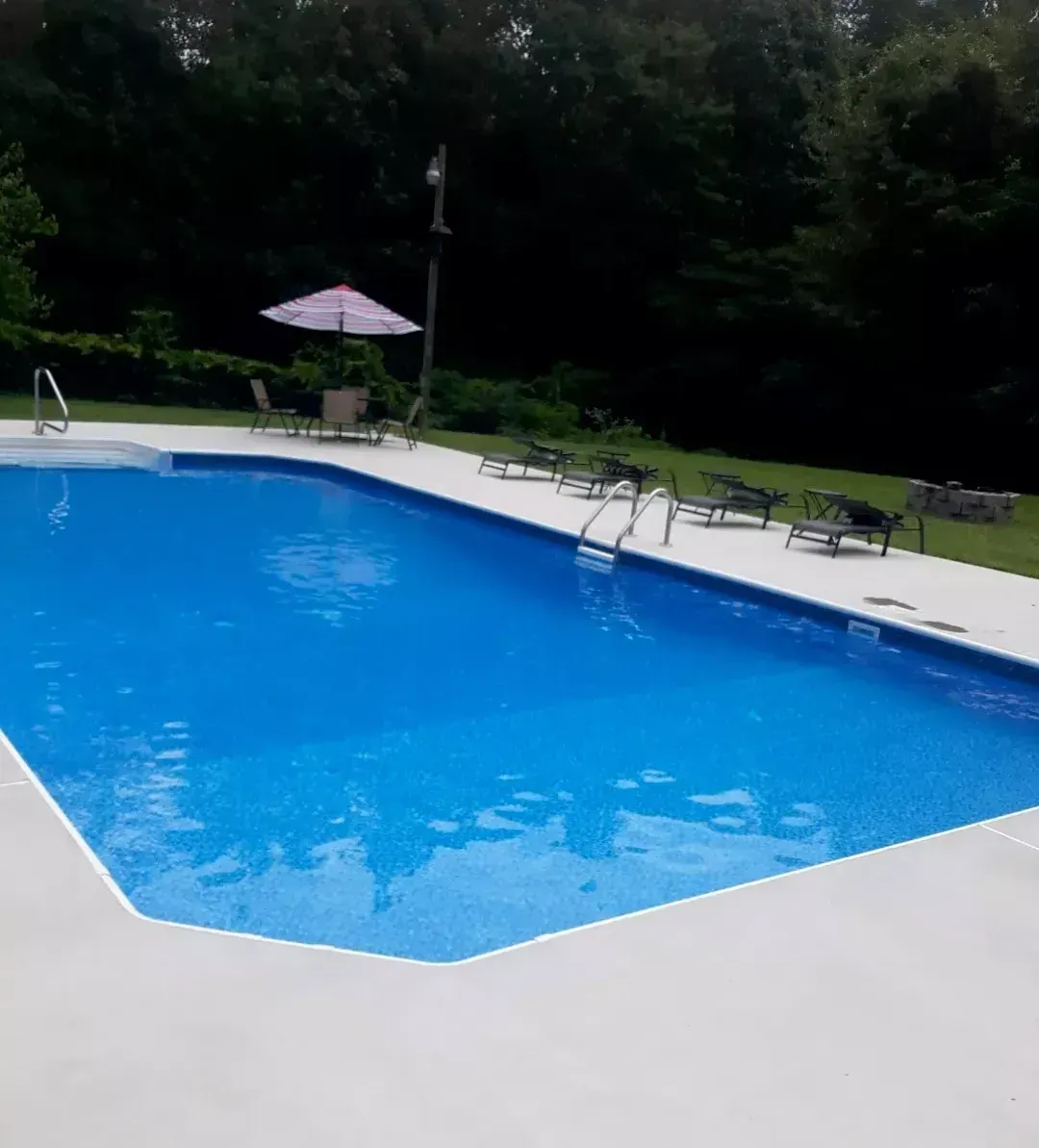 A large swimming pool surrounded by chairs and umbrellas