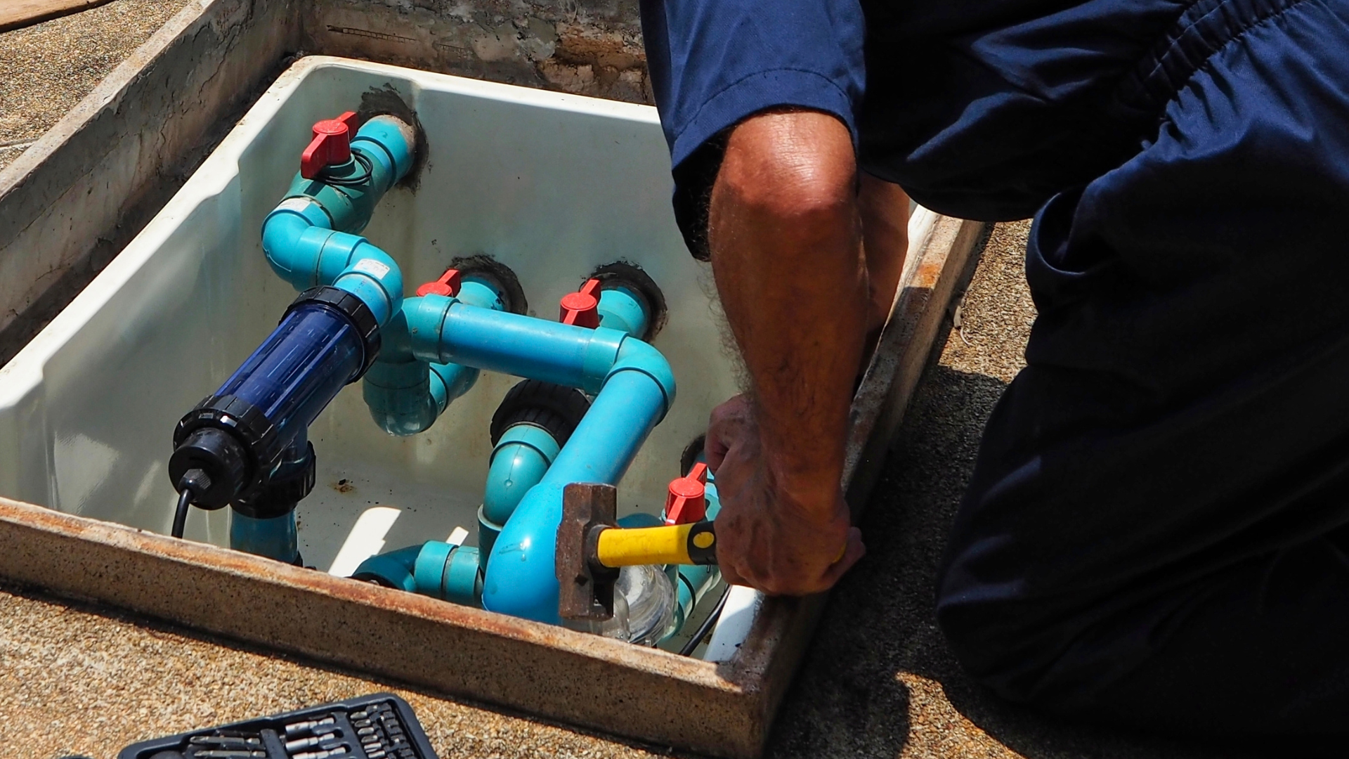 A man is working on a pipe with a hammer
