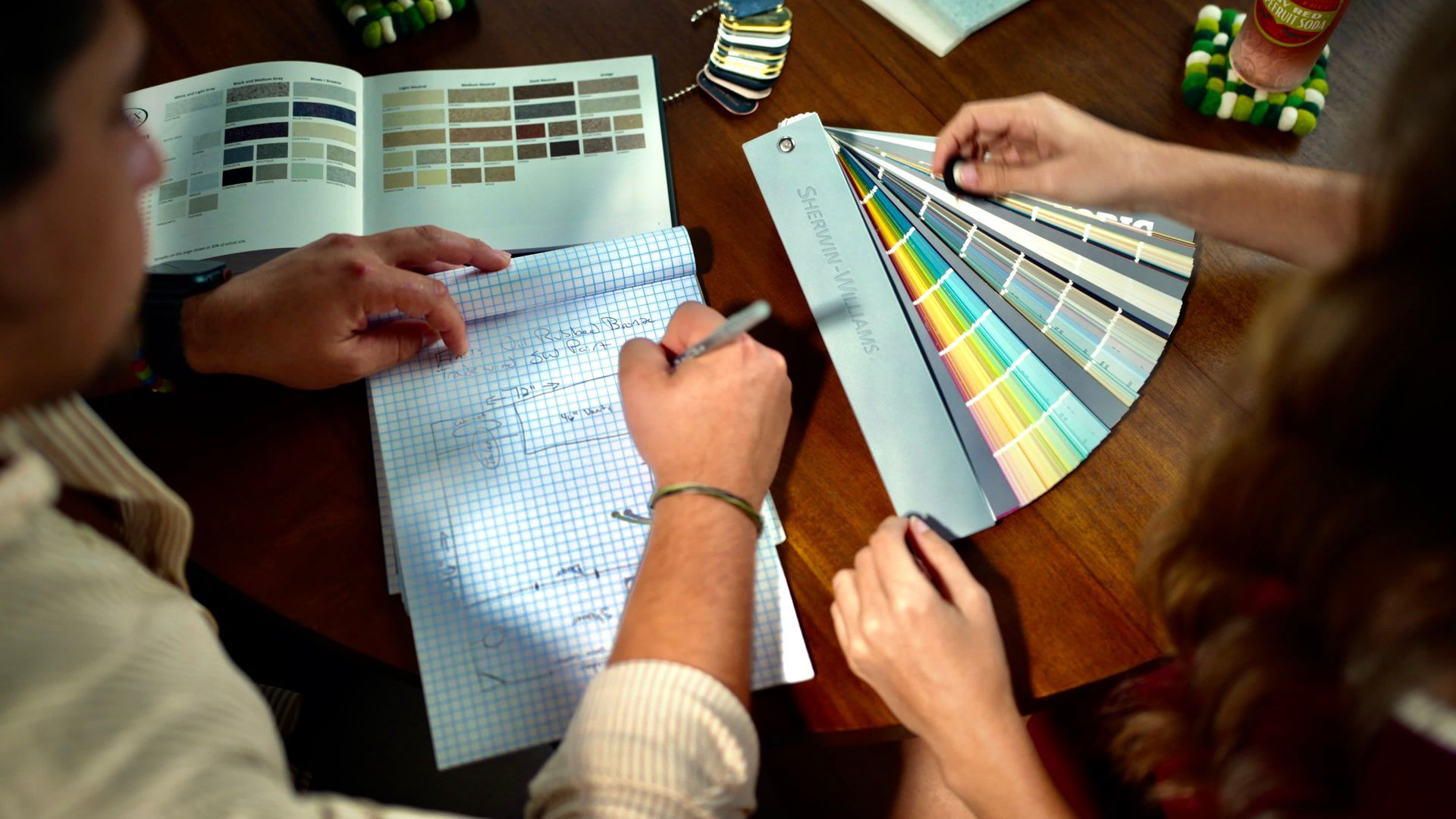 Two people at a table reviewing paint swatches and taking notes for a bathroom remodel.