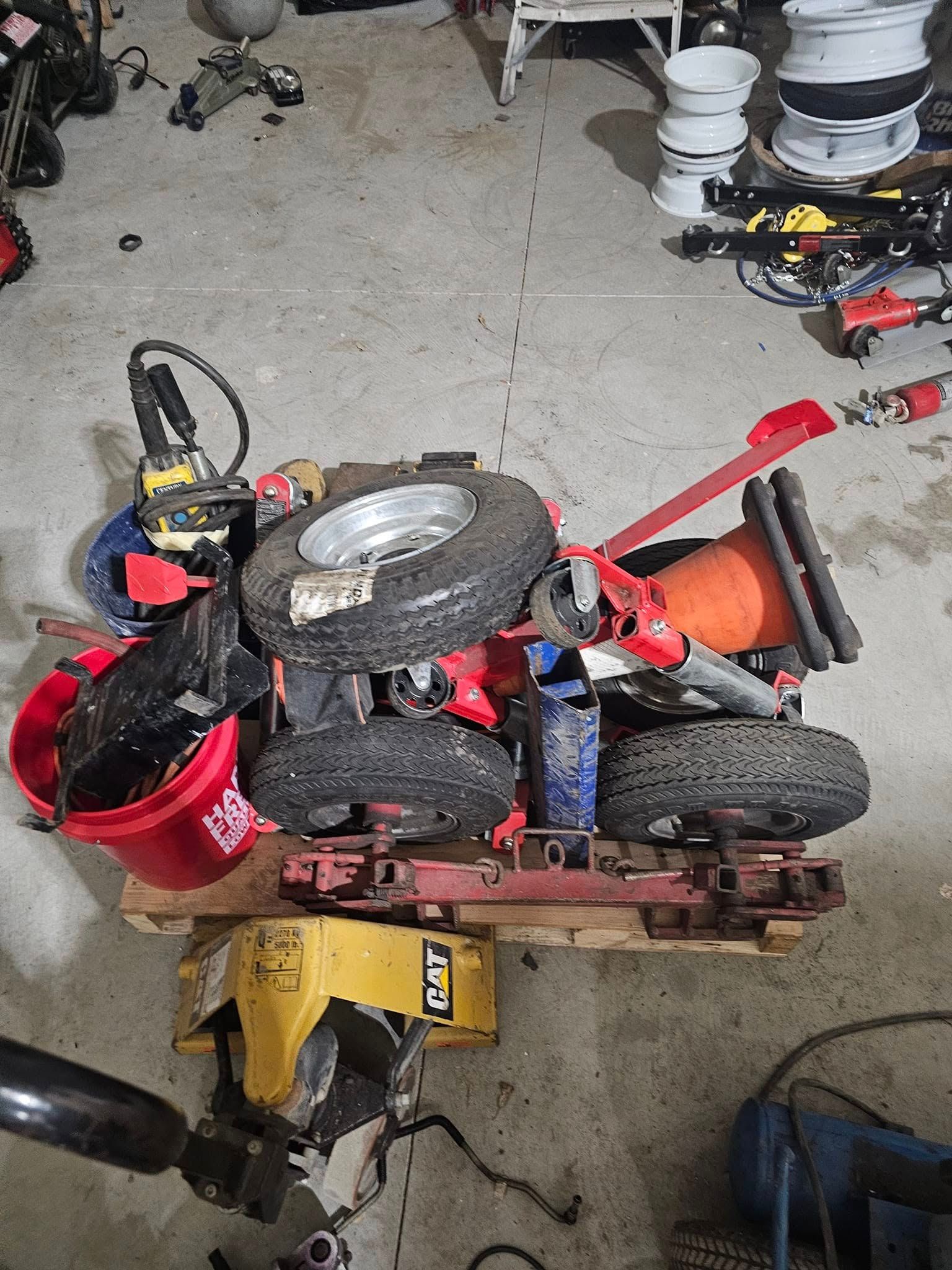 Pile of tires, tools, and equipment on a pallet in a garage.
