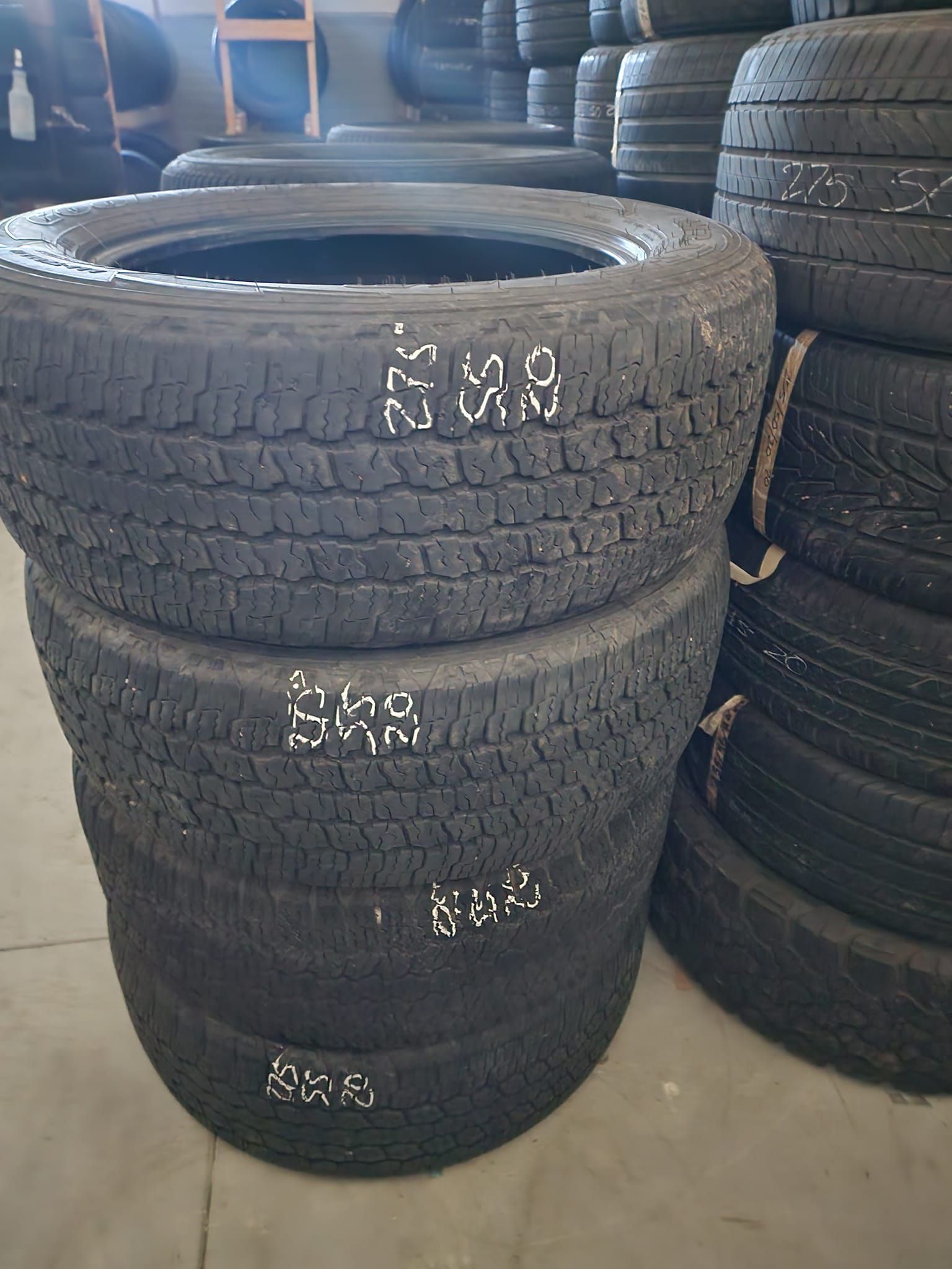 Pile of used tires with white markings, inside a building.