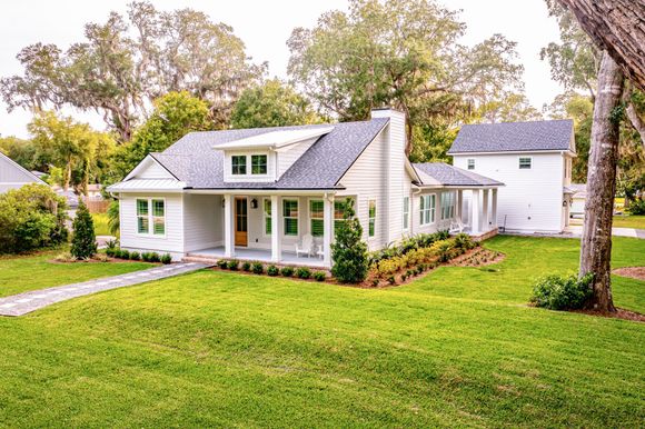 A white house with a large lawn in front of it.