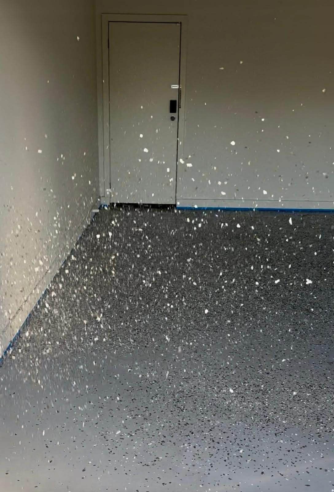 flakes being broadcast and spread on a plain epoxy floor