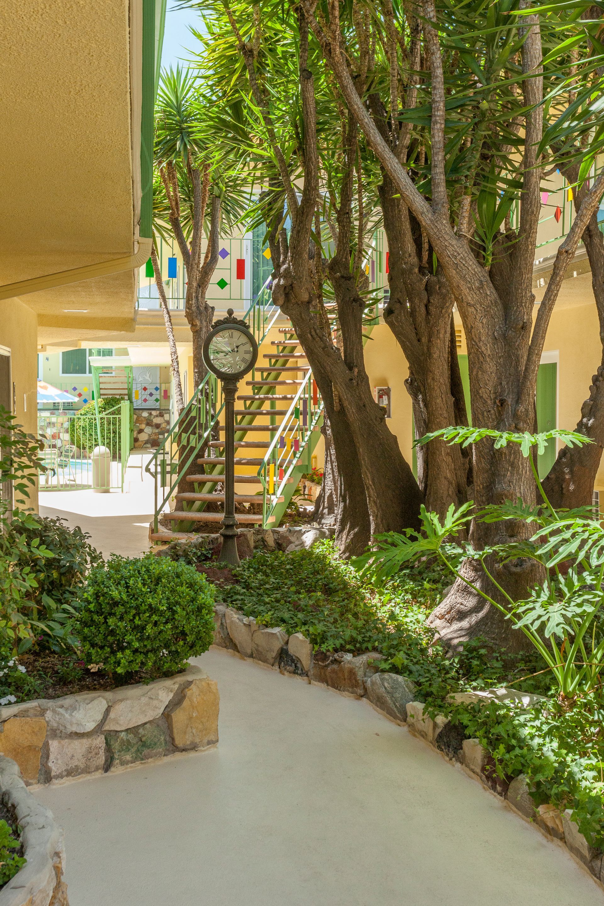 A clock is sitting in the middle of a garden surrounded by trees.