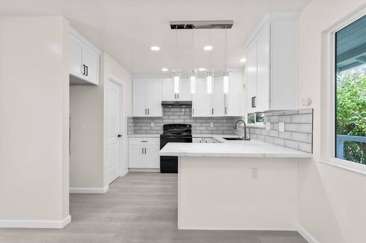 Woman in straw hat smiles, holding wine glass near a lake.