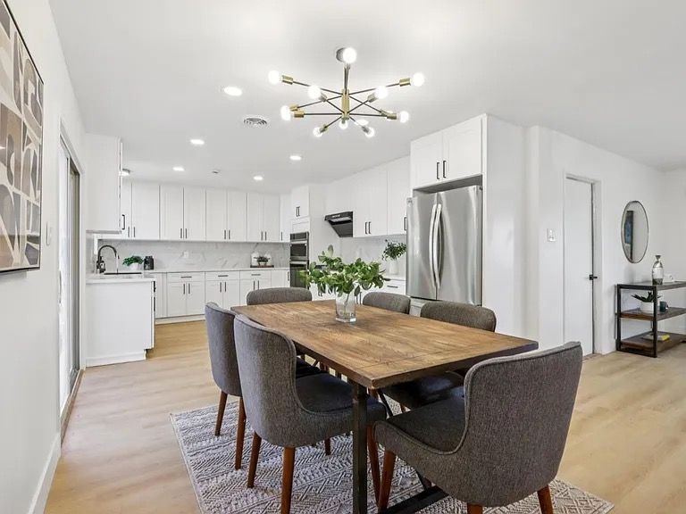 Woman in straw hat smiles, holding wine glass near a lake.