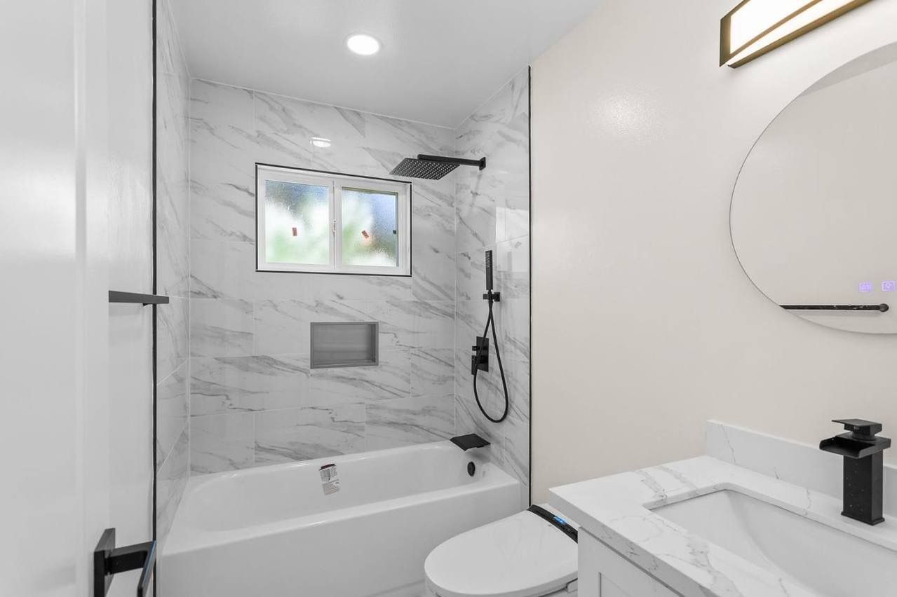 Woman in straw hat smiles, holding wine glass near a lake.