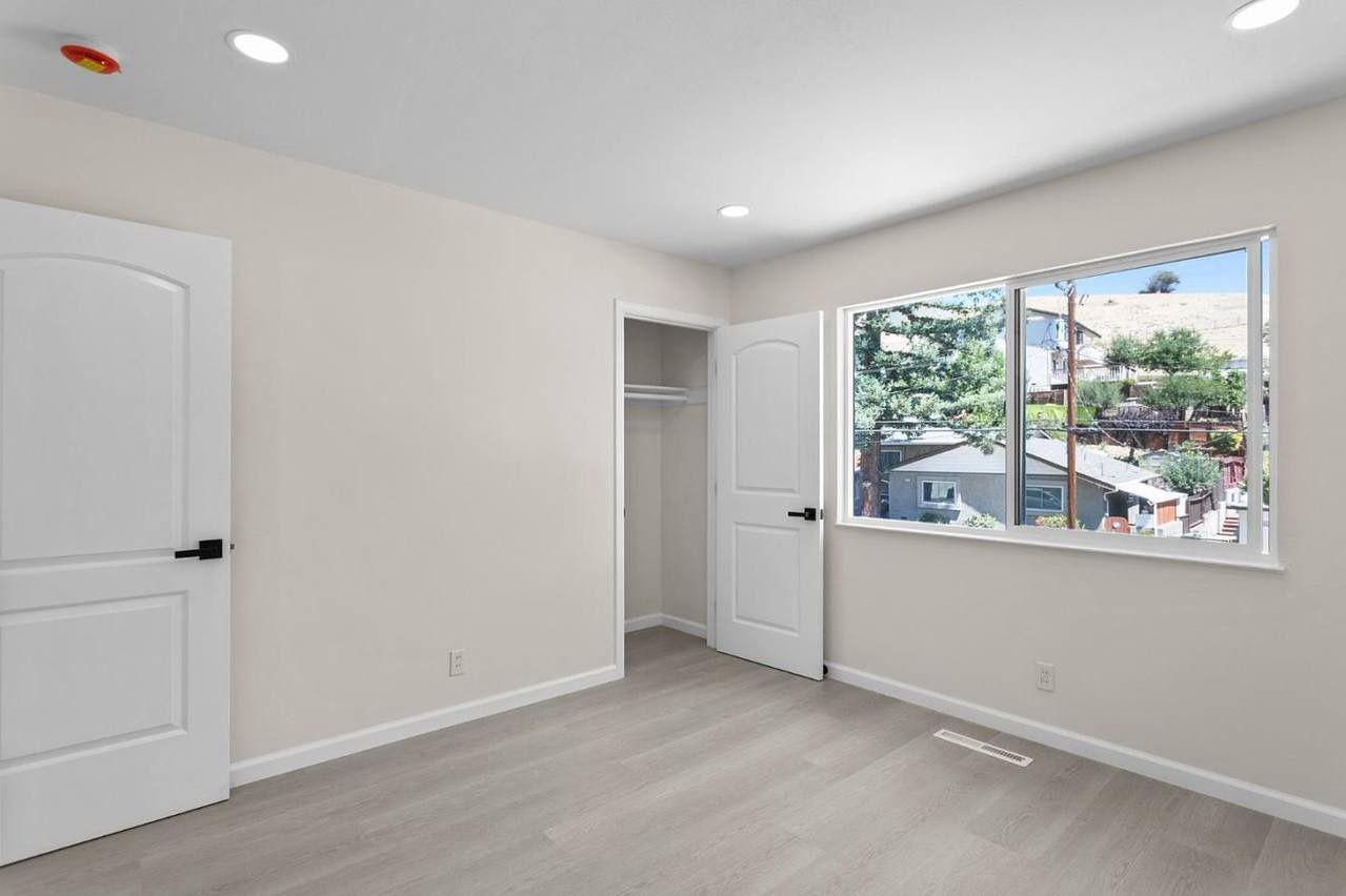 Woman in straw hat smiles, holding wine glass near a lake.