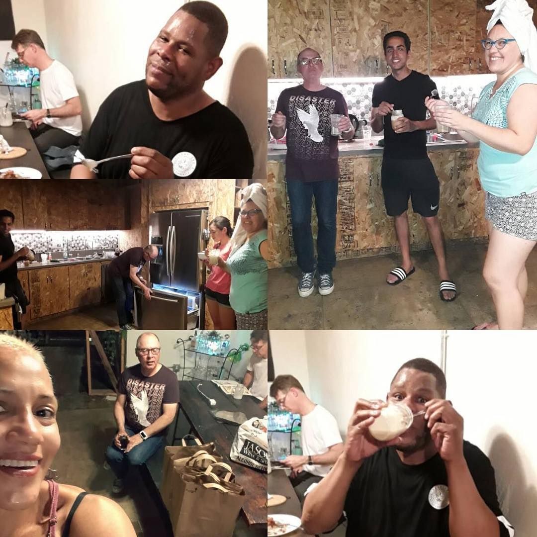 People indoors preparing or eating food, smiling. One man eats a marshmallow.