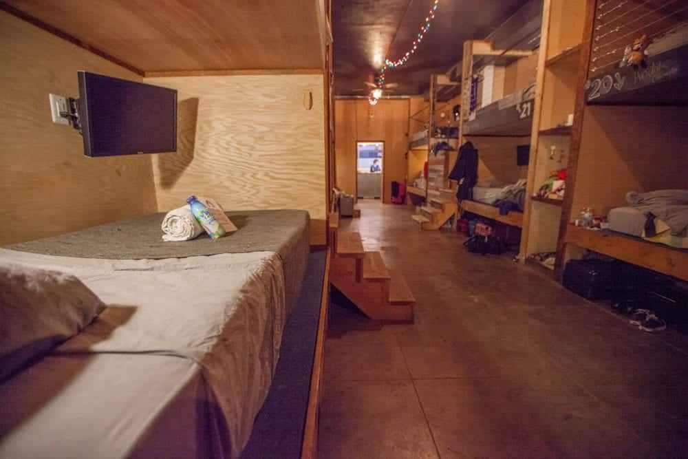 Dorm room: Bunk beds line a long hallway. One bed has a TV on the wall.