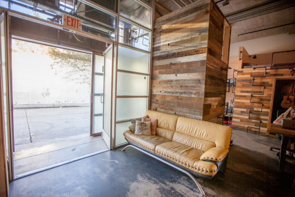 Open doorway with leather couch and rustic wood walls.