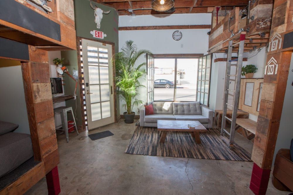 Bunk beds flank a living area with a sofa, coffee table, and open door with an exit sign.