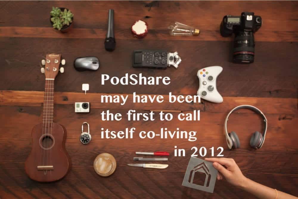 Wooden table with various objects, including a ukulele, camera, and text stating PodShare was the first co-living space in 2012.