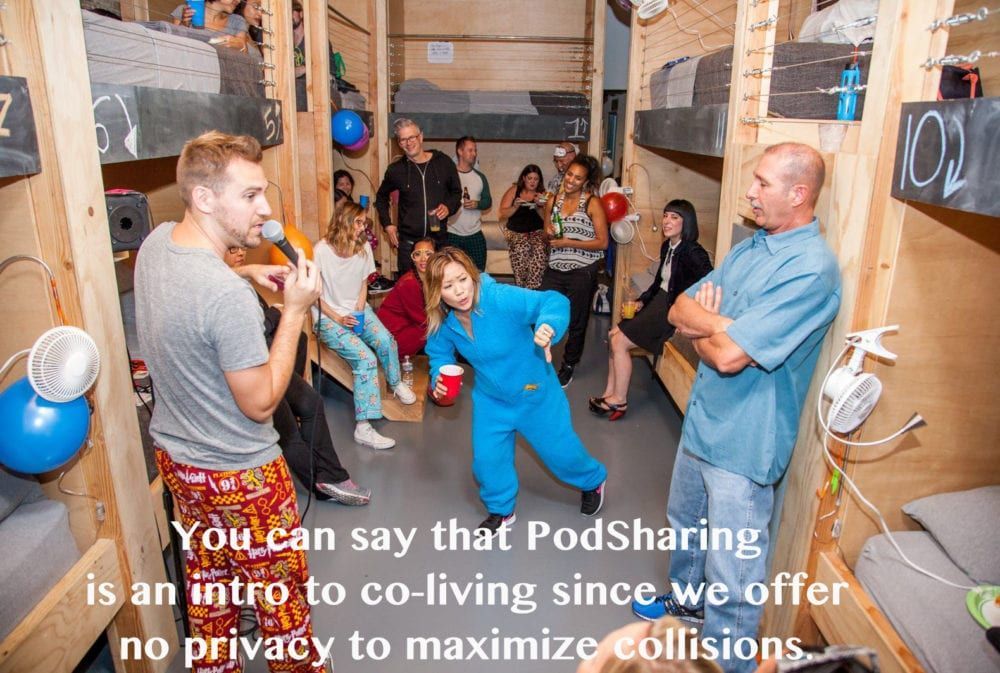 People in a co-living space, one speaking into a mic. Bunk beds line the walls. Text: 