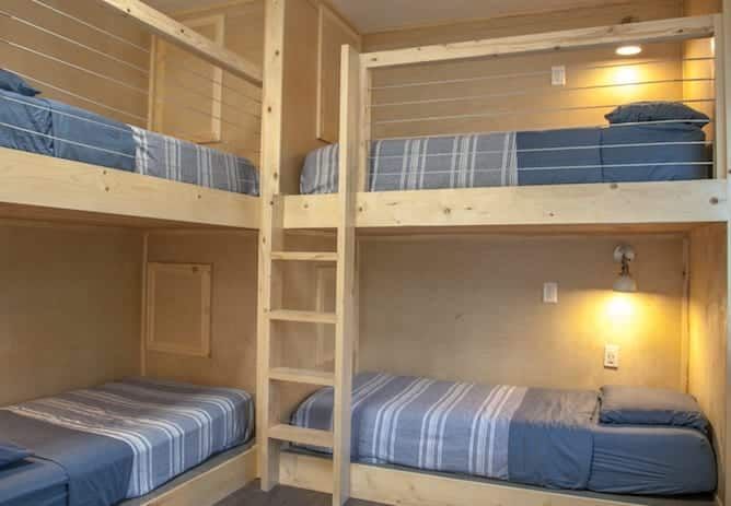 Bunk beds in a room with a light wood frame and blue-striped bedding.
