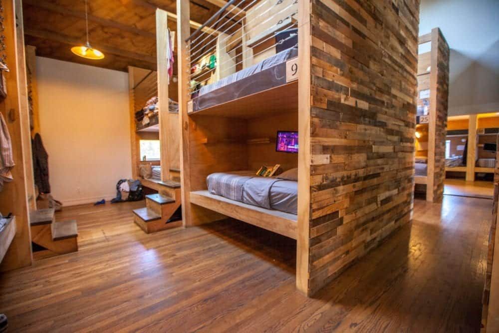 Wooden bunk beds in a room with wood flooring and walls; the beds are in individual cubicles.