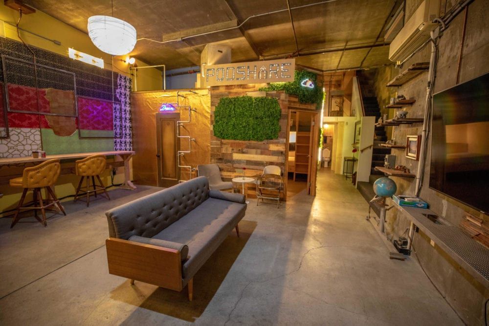 Eclectic living space with gray couch, bar, loft, and Sesame Street-themed decor.