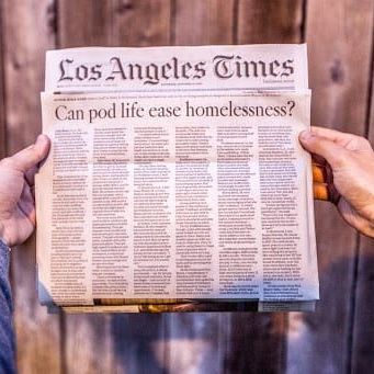 Person holding a Los Angeles Times newspaper with the headline, 