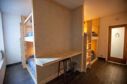 Bunk beds in a room with a desk and a door, wooden structure, interior shot.