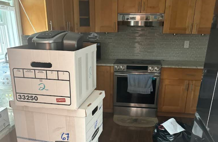A kitchen with packed boxes, oven, and cabinets; looks like a move is in progress.