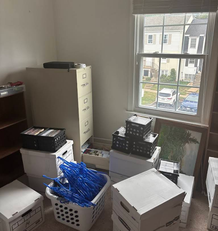 Cluttered room: boxes, baskets, filing cabinet, and window with a street view.