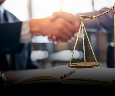 Dois homens apertando as mãos diante de uma balança de justiça.