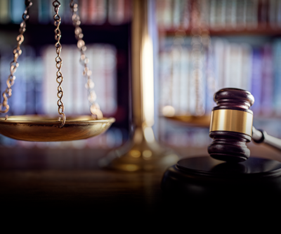 Uma balança de justiça e um martelo de juiz estão sobre a mesa de um tribunal.