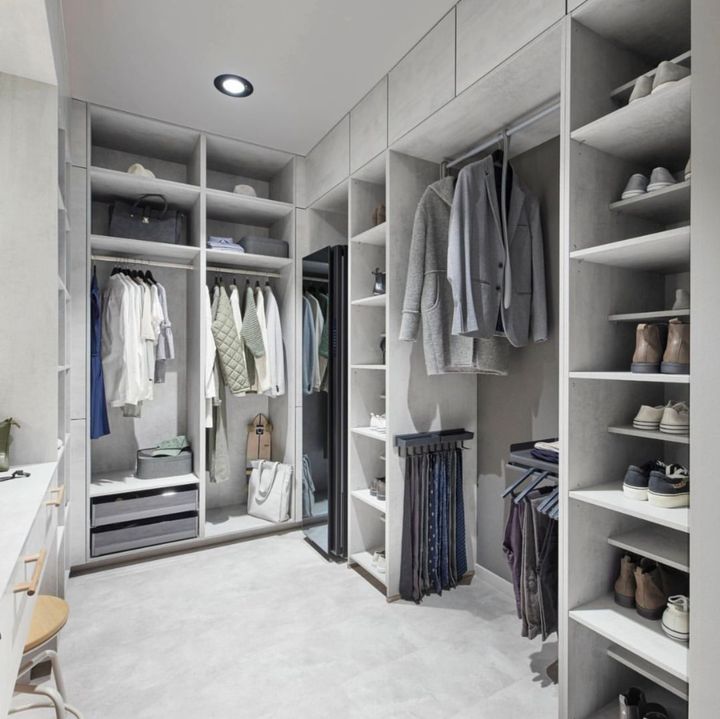 Walk-in closet with light gray shelves, clothing, shoes, and a mirror.