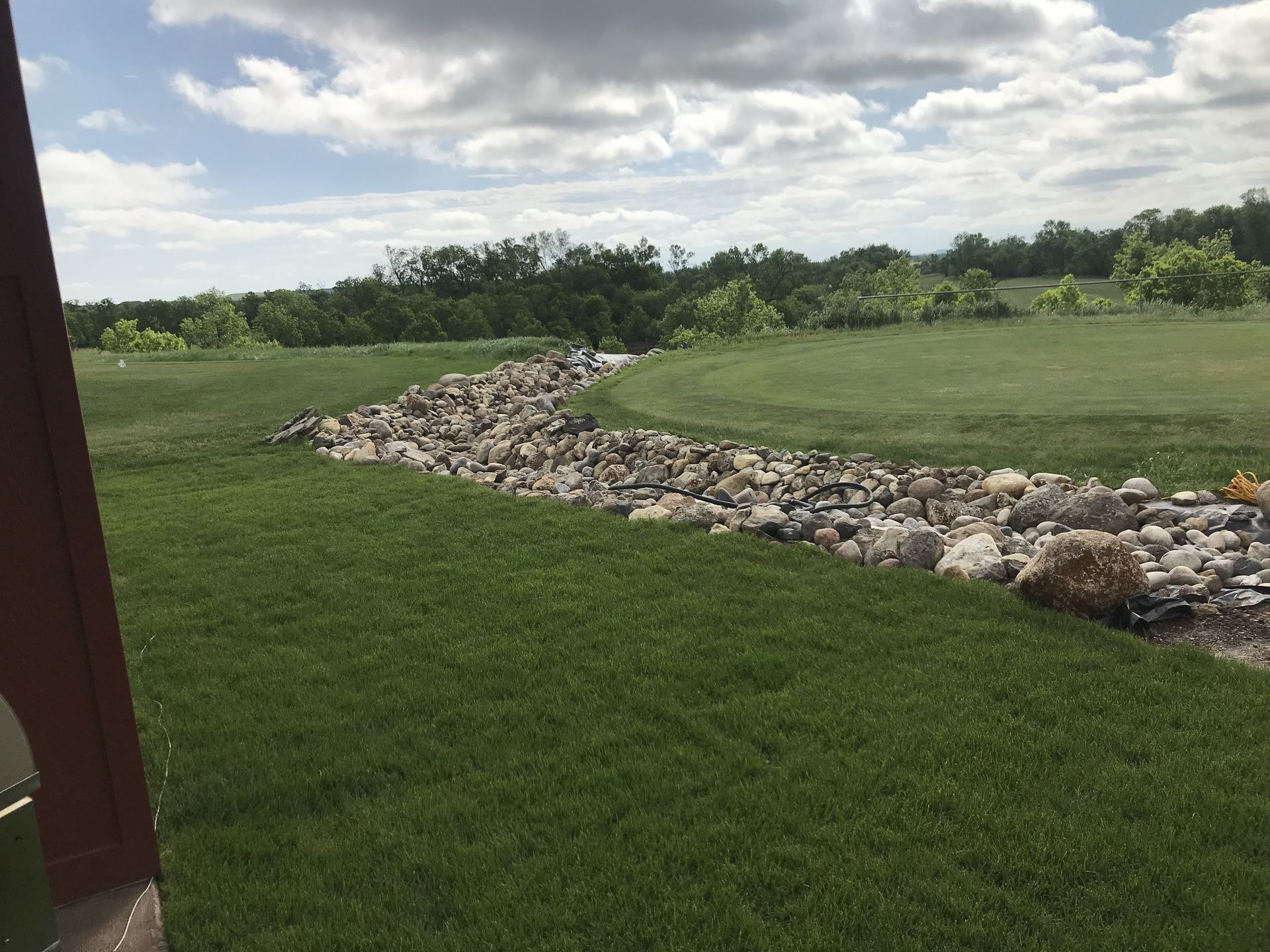 Fallen tree on the side of a house, blue sky, tree branches covering roof and siding.