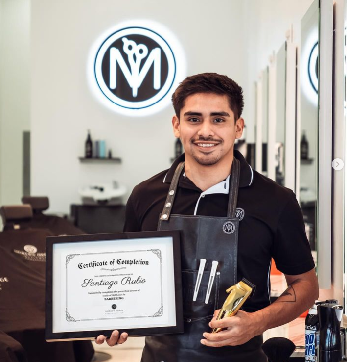 A man in an apron is holding a framed certificate