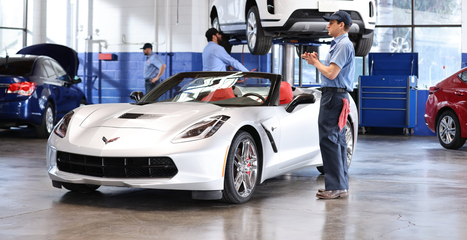A man is standing next to a white sports car in a garage.