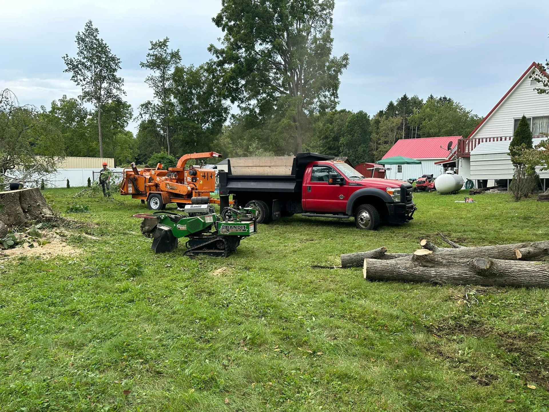 A red truck is parked in a grassy field next to a tree stump.