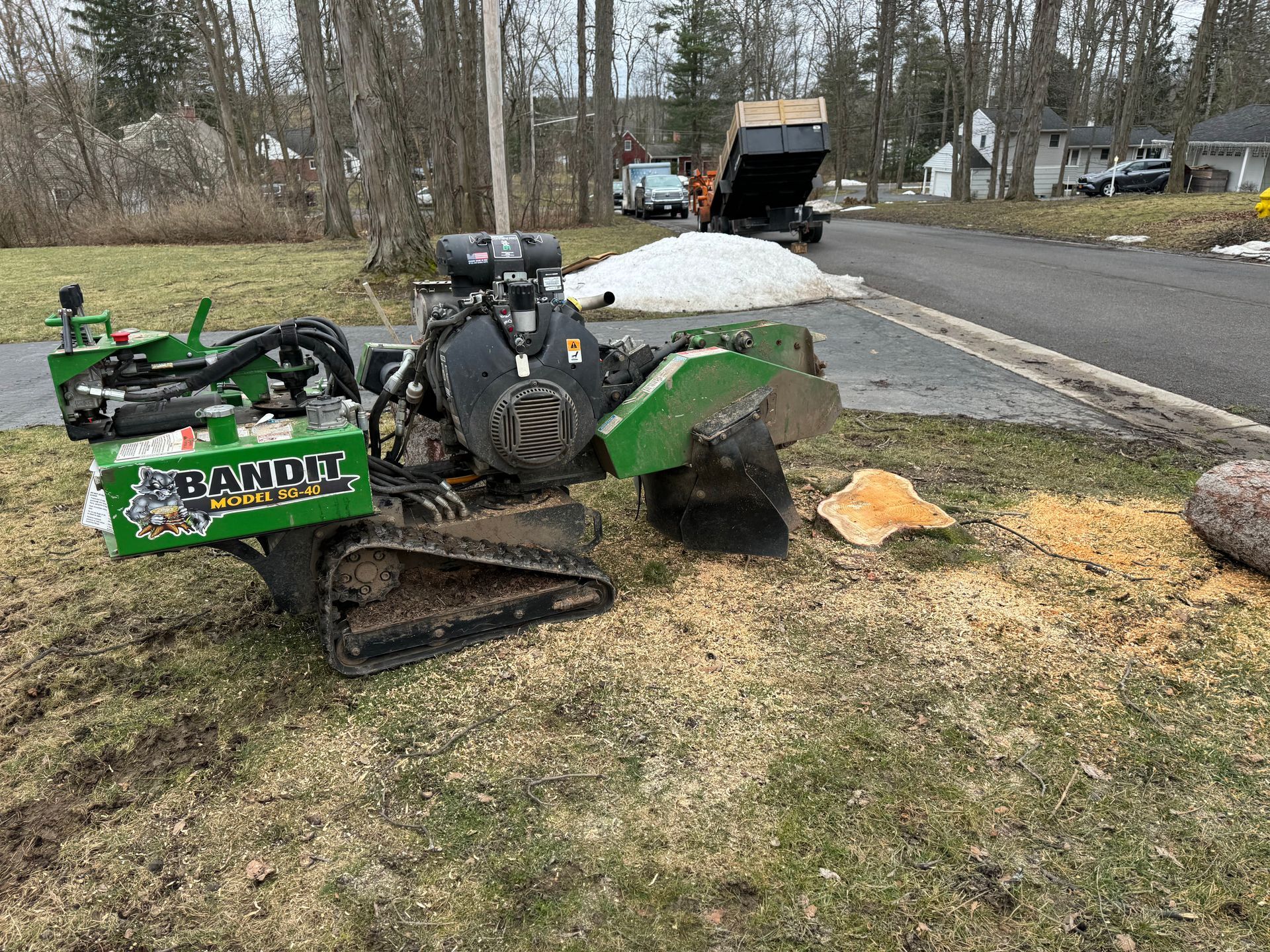A stump grinder is sitting on top of a stump in the grass.